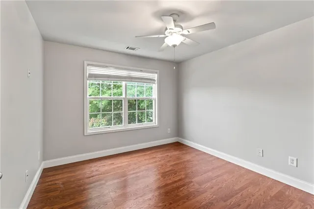 an empty room with wooden floor fan and windows