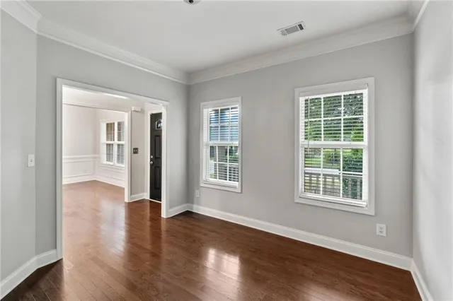 a view of an empty room with wooden floor and a window