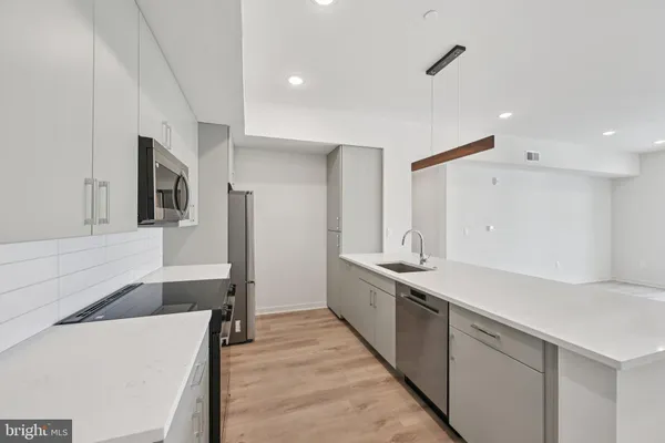 a large white kitchen with a sink and dishwasher a refrigerator with wooden floor