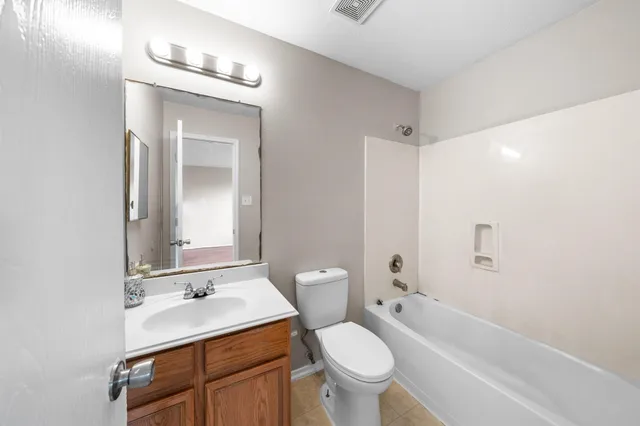 a bathroom with a toilet a sink a mirror a bathtub and vanity