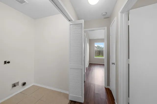 a view of a hallway with wooden floor and a bathroom