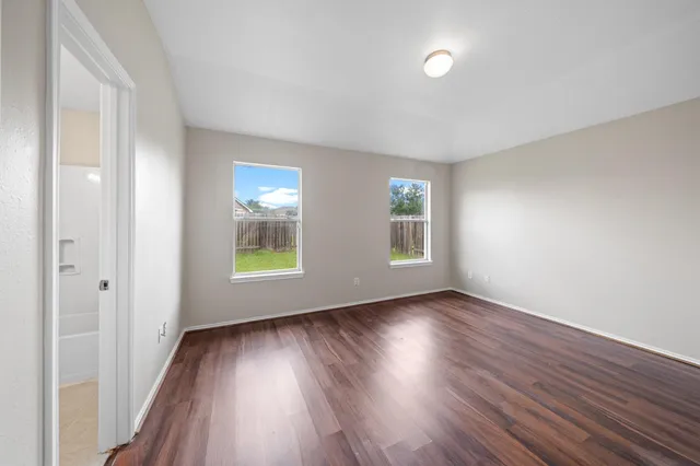 an empty room with wooden floor and windows