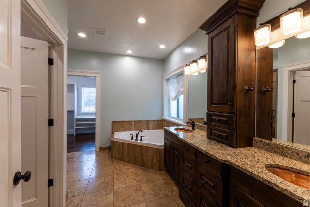 3565 West 1350th Street North Vernal, UT 84078 - Photo 20 of 54 Spacious bathroom featuring a built-in jetted tub with tile surround, dual vanity with stone countertops and copper vessel sinks, and dark wood cabinetry