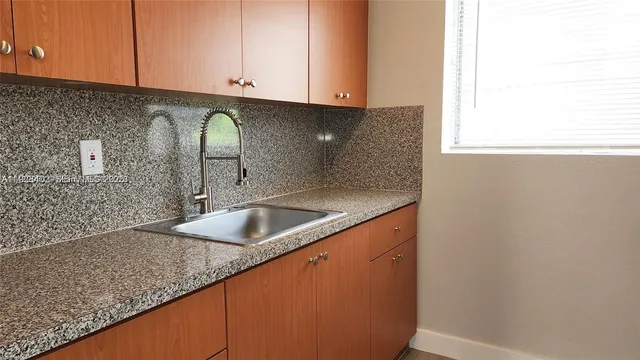 a kitchen with granite countertop a sink and a white cabinets