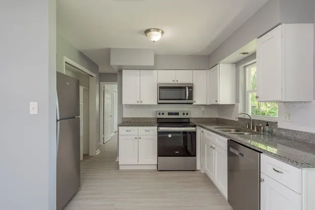 a kitchen with stainless steel appliances granite countertop a stove a sink and a refrigerator