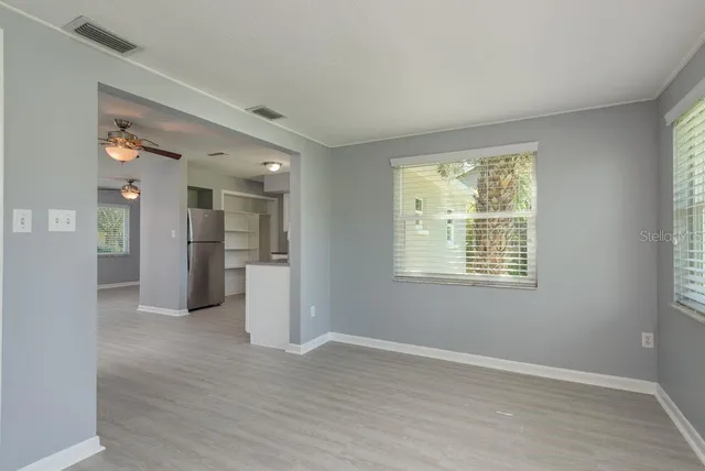 a view of an empty room with a window and wooden floor