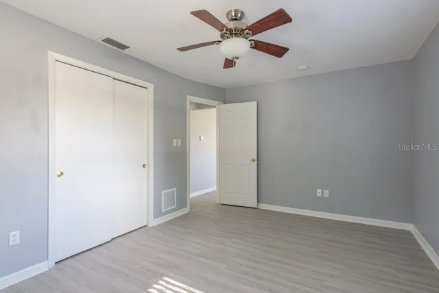 an empty room with wooden floor and a ceiling fan