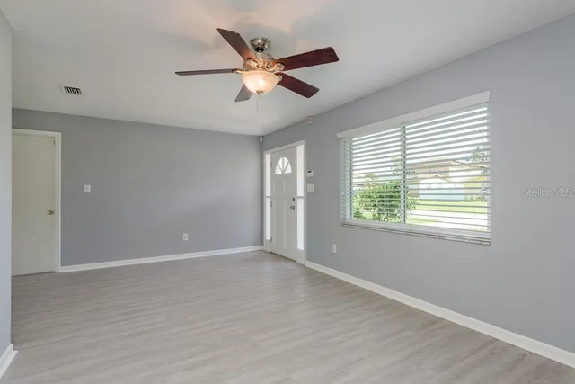 a view of an empty room with wooden floor and a window