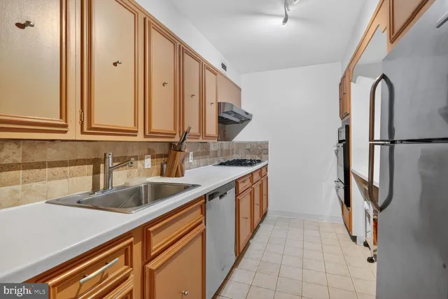 a kitchen with stainless steel appliances granite countertop a sink and a refrigerator