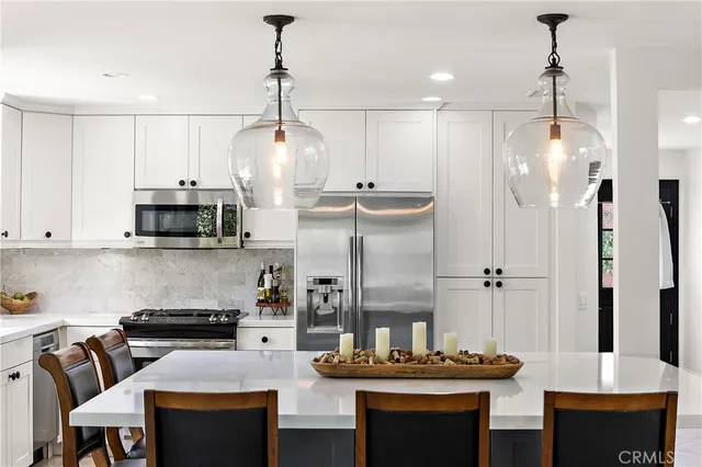 a kitchen with stainless steel appliances kitchen island granite countertop a table and chairs in it