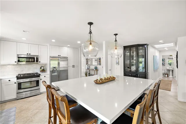 a kitchen with stainless steel appliances kitchen island granite countertop a dining table chairs and white cabinets
