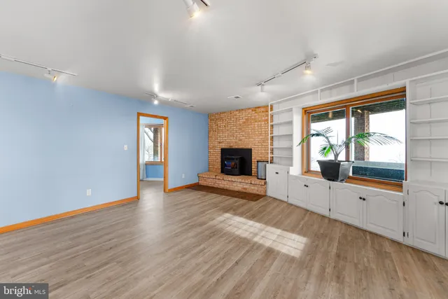 a view of an empty room with window and wooden floor