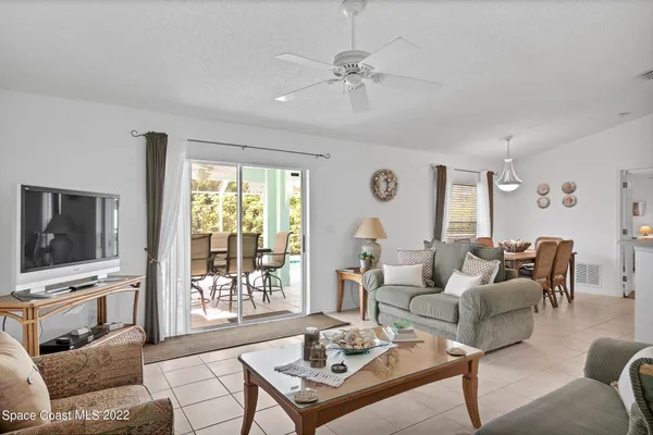 a living room with furniture a flat screen tv and a floor to ceiling window