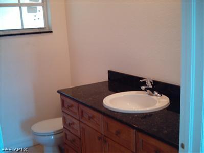 Undisclosed Address Lehigh Acres, FL 33974 - Photo 6 of 7 a bathroom with a toilet sink and mirror
