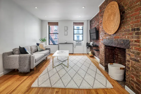 a living room with furniture a fireplace a rug and wooden floor