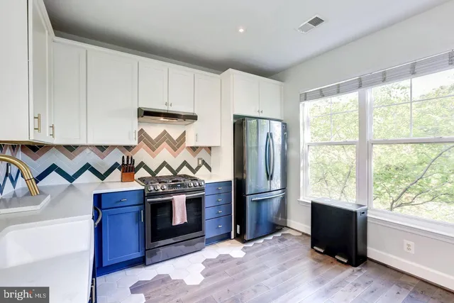 a kitchen with stainless steel appliances granite countertop a refrigerator a stove and a sink