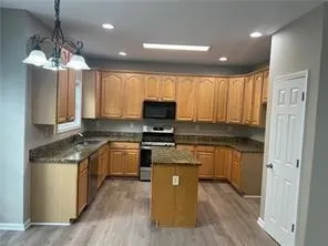 a kitchen with granite countertop a stove top oven a sink dishwasher a dining table and chairs with wooden floor