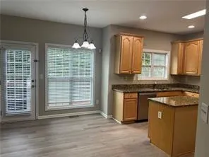 a kitchen with kitchen island granite countertop a sink cabinets and wooden floor