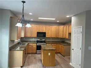a kitchen with kitchen island granite countertop a sink cabinets and stainless steel appliances