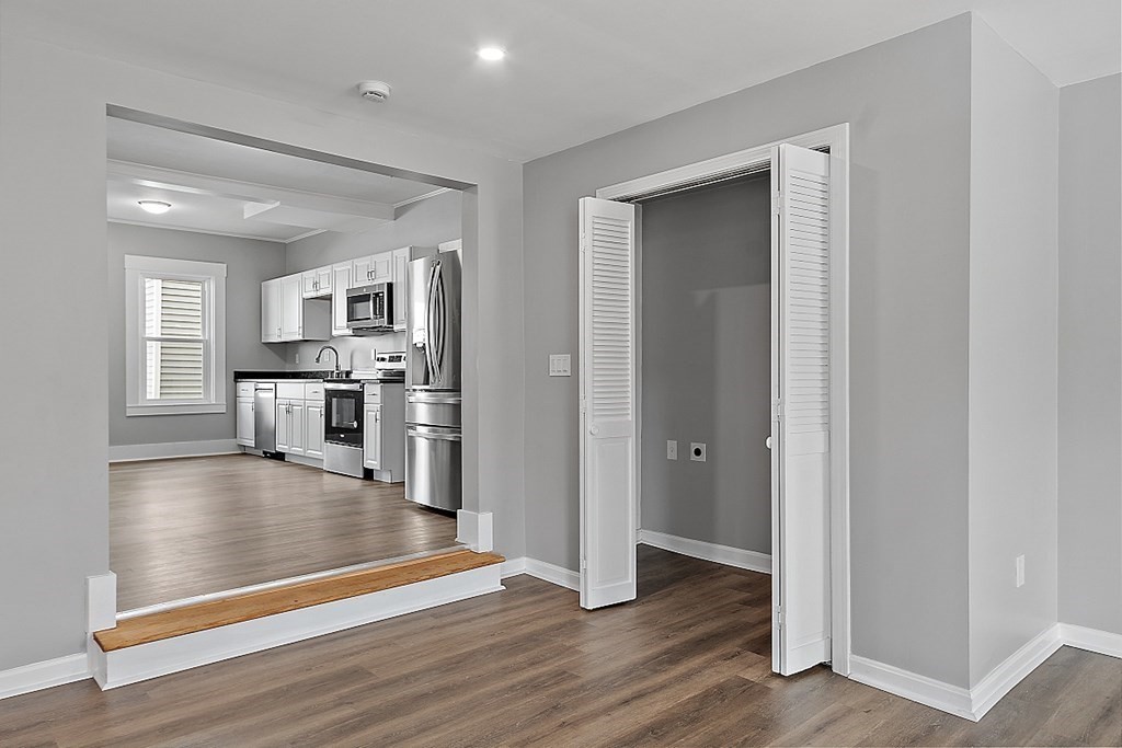 46 West Meadow Road Lowell, MA 01854 - Photo 15 of 42 an empty room with wooden floor and a kitchen