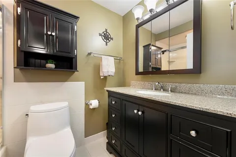 a bathroom with a granite countertop toilet sink and mirror