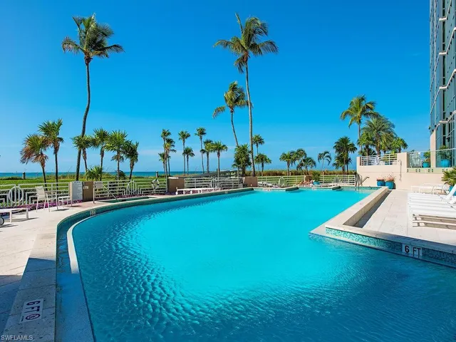 a view of a swimming pool with a yard and palm trees