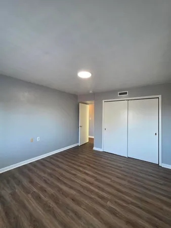 a view of an empty room with wooden floor and window