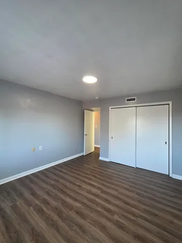 a view of an empty room with wooden floor and window