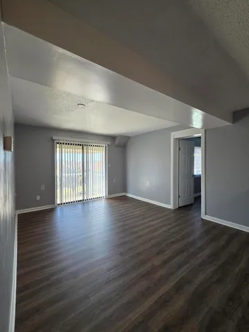 a view of an empty room with wooden floor and window