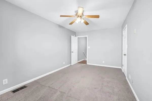 an empty room with closet and a ceiling fan