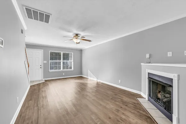 a view of an empty room with wooden floor fireplace and a window