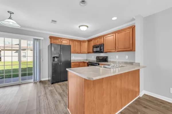 a kitchen with stainless steel appliances granite countertop a refrigerator a sink a stove and white cabinets with wooden floor
