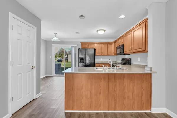 a kitchen with stainless steel appliances granite countertop a refrigerator a stove and a sink with wooden floor