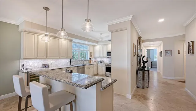 a kitchen with stainless steel appliances granite countertop a sink a refrigerator a stove a kitchen island with a dining table and chairs