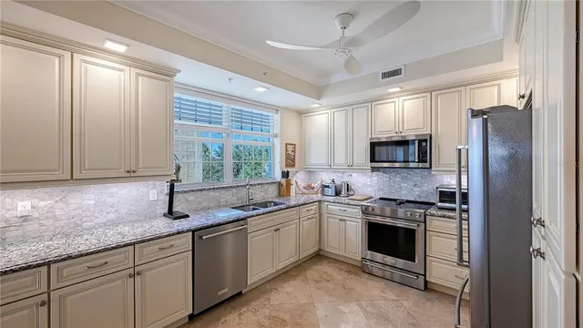 a kitchen with stainless steel appliances granite countertop white cabinets a sink and a window