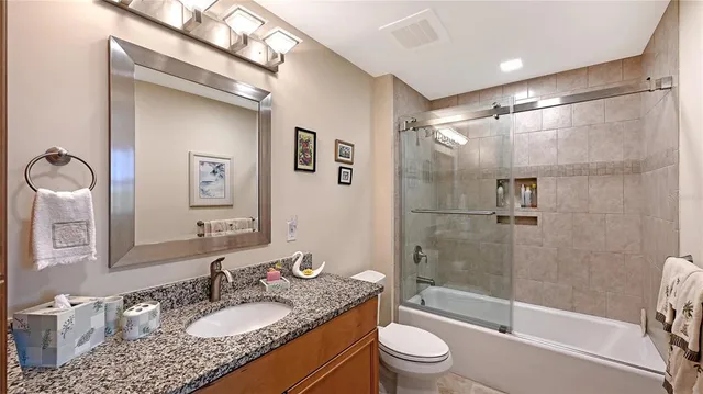 a bathroom with a granite countertop sink toilet mirror and shower