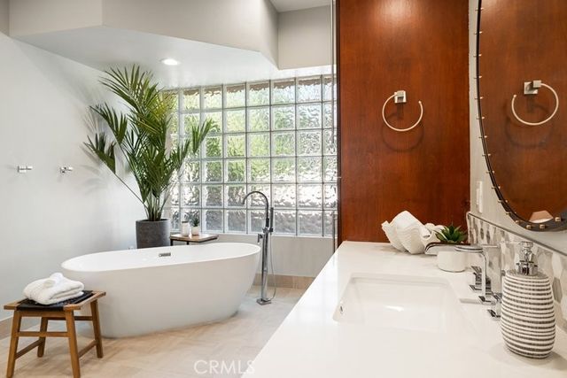 a bathroom with a tub a potted plant and a window