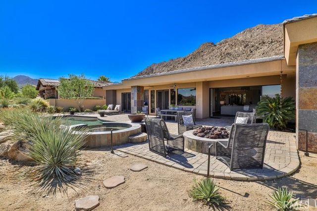 a view of a patio with couches table and chairs under an umbrella with a barbeque