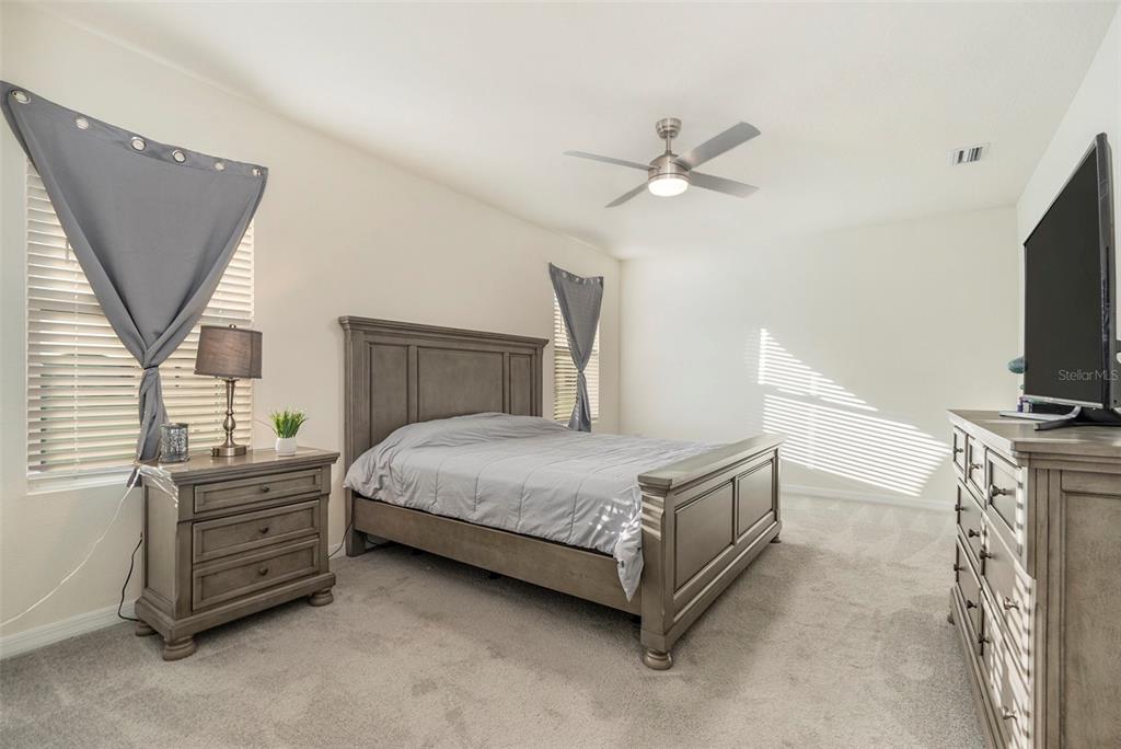 9319 Forge Breeze Loop Wesley Chapel, FL 33545 - Photo 18 of 45 a bedroom with a bed and a flat screen tv