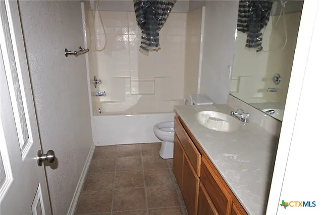 an empty room with a chandelier fan and a window