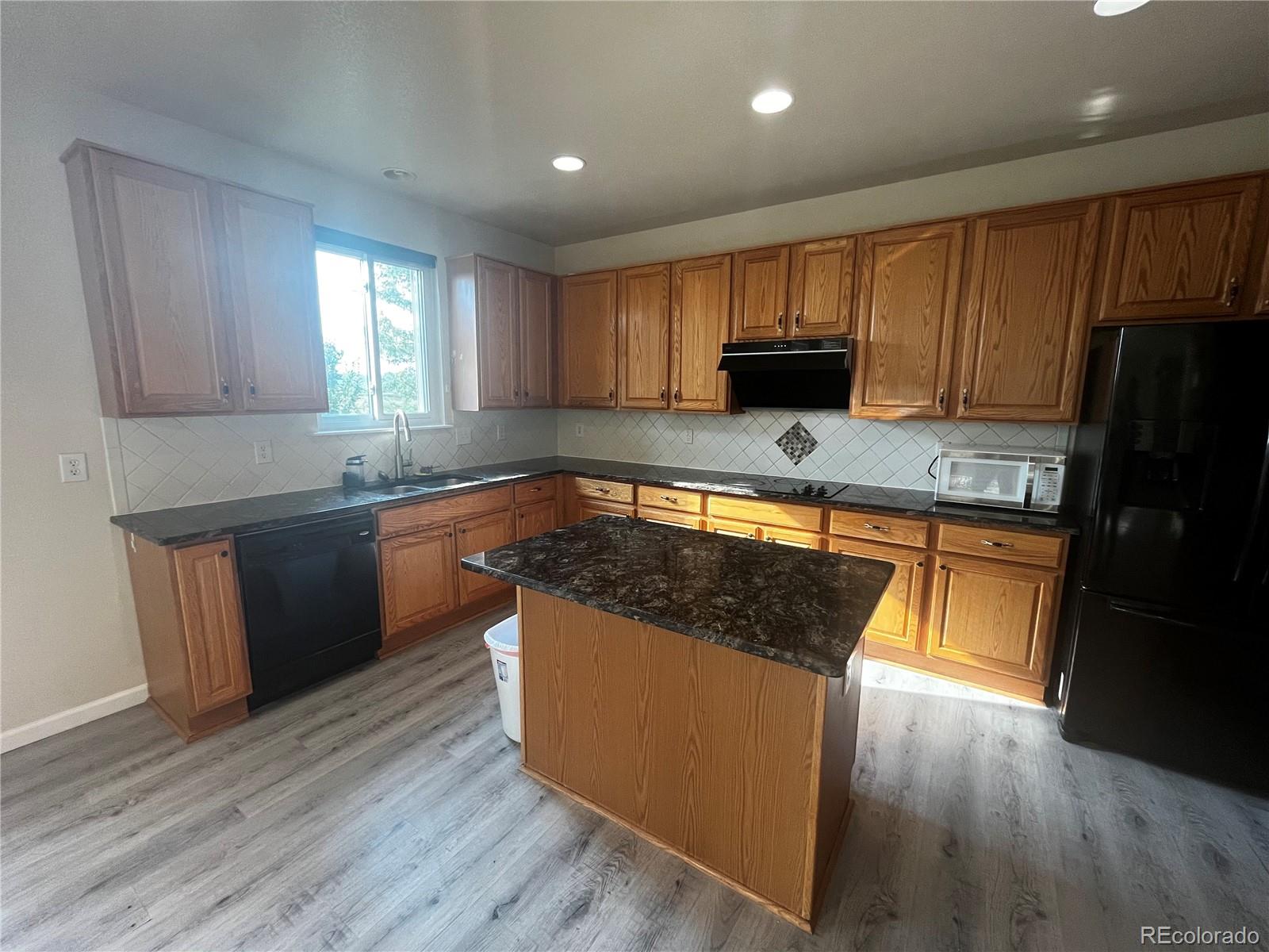 8121 Raspberry Drive Frederick, CO 80504 - Photo 9 of 27 a kitchen with stainless steel appliances granite countertop wooden cabinets a refrigerator a sink a stove a microwave and wooden floors