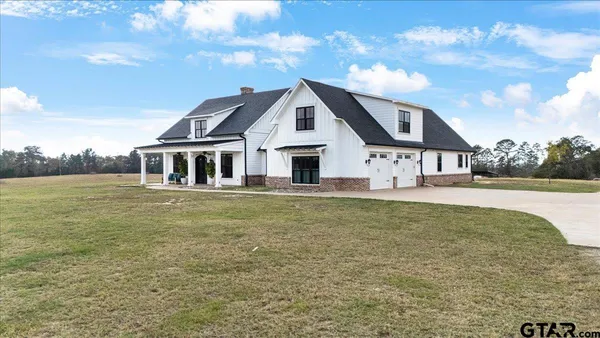 a view of a house with floor to ceiling windows and a yard