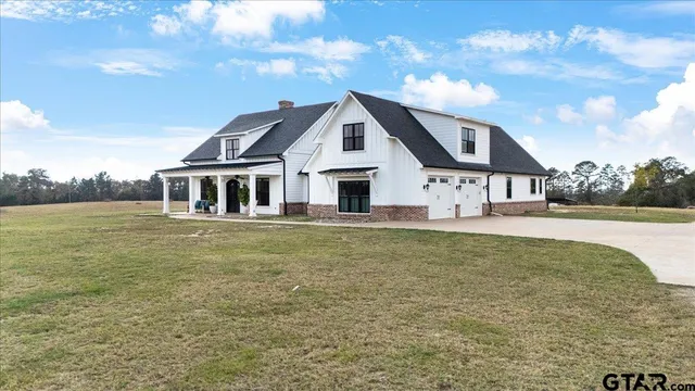 a view of a house with floor to ceiling windows and a yard