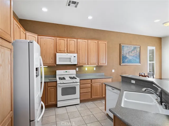 a kitchen with stainless steel appliances granite countertop a refrigerator a stove a sink dishwasher and white cabinets with wooden floor