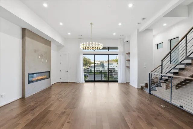a view of an empty room with wooden floor entryway and a window