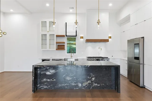 a kitchen with stainless steel appliances granite countertop a sink a stove and refrigerator