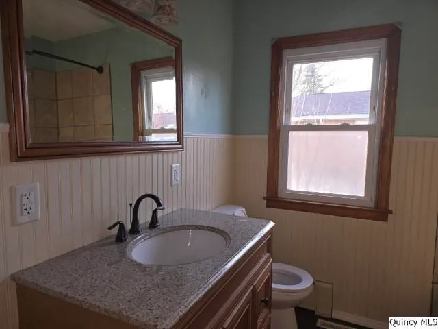 a bathroom with a granite countertop sink toilet a mirror and window