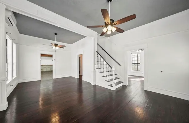 a view of an empty room with wooden floor and a ceiling fan