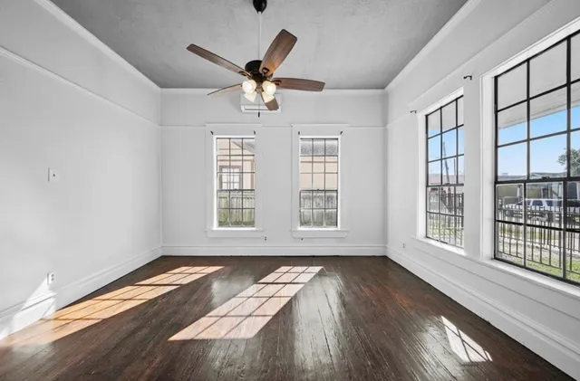 a view of an empty room with wooden floor and a window