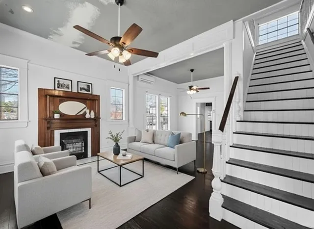 a living room with furniture a fireplace and a ceiling fan